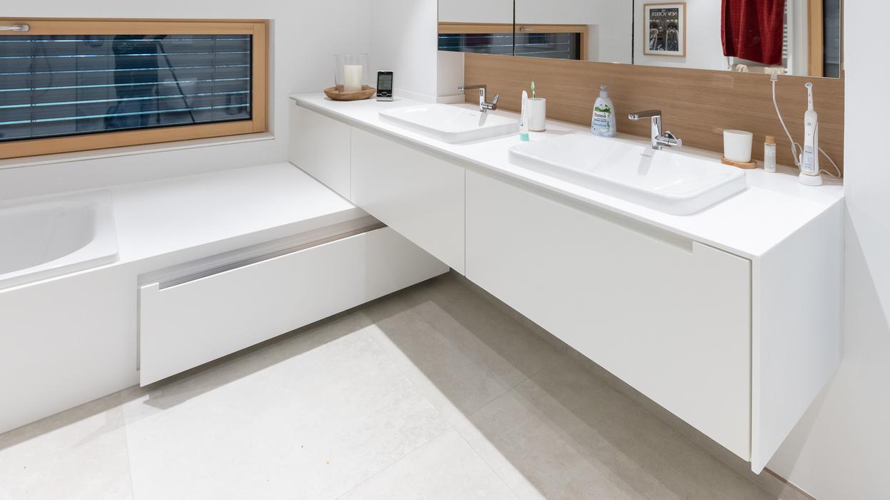 Modernes Badezimmer mit Badmöbeln nach Maß Ein minimalistisches Badezimmer mit großem Spiegel, Doppelwaschbecken und nach Maß gefertigten weißen Badmöbeln.