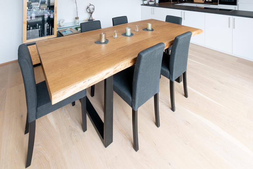 Offene Küche nach Maß mit Essbereich Luftiger Essbereich mit Holztisch und grauen Stühlen, angrenzend an eine weiße, maßgeschneiderte Küche.