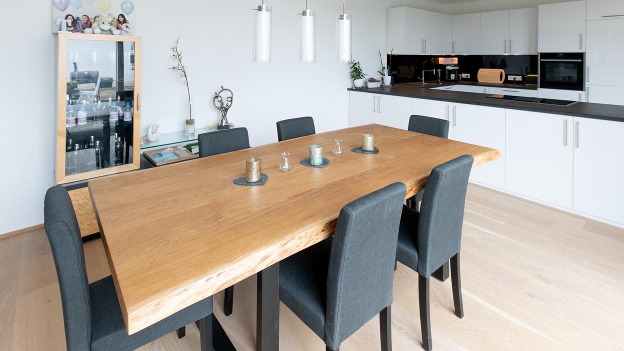 Offene Küche nach Maß mit Essbereich Luftiger Essbereich mit Holztisch und grauen Stühlen, angrenzend an eine weiße, maßgeschneiderte Küche.