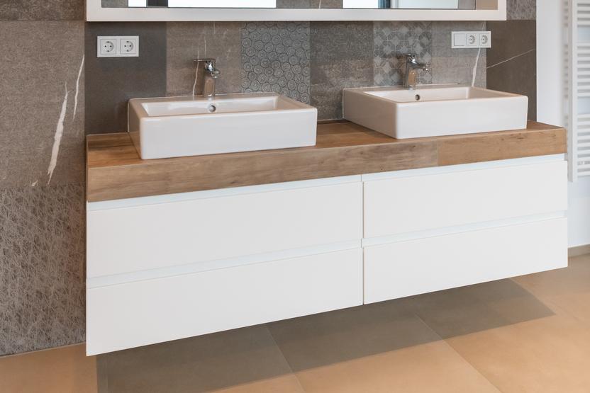 Badezimmer mit Doppelwaschtisch, rechteckigen Waschbecken, Holzarbeitsfläche, großem Spiegel und dekorativen grauen Fliesen in geometrischen Mustern.