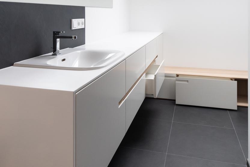 Modernes, gut beleuchtetes Badezimmer mit schlichten, nach Maß gefertigten Badmöbeln unter Dachschrägenfenstern.