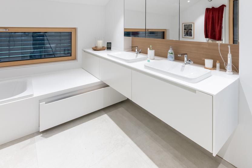 Ein minimalistisches Badezimmer mit großem Spiegel, Doppelwaschbecken und nach Maß gefertigten weißen Badmöbeln.