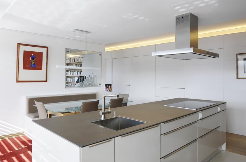 Küche mit Kochinsel nach Maß mit weißen Fronten und silberner Oberfläche