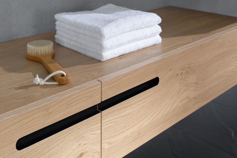 Detailaufnahme eines schmalen Waschtischunterschrankes aus Massivholz mit eingelassenen Griffen